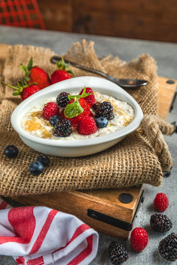 Bowl of oatmeal topped with raspberries, blackberries, blueberries and mint